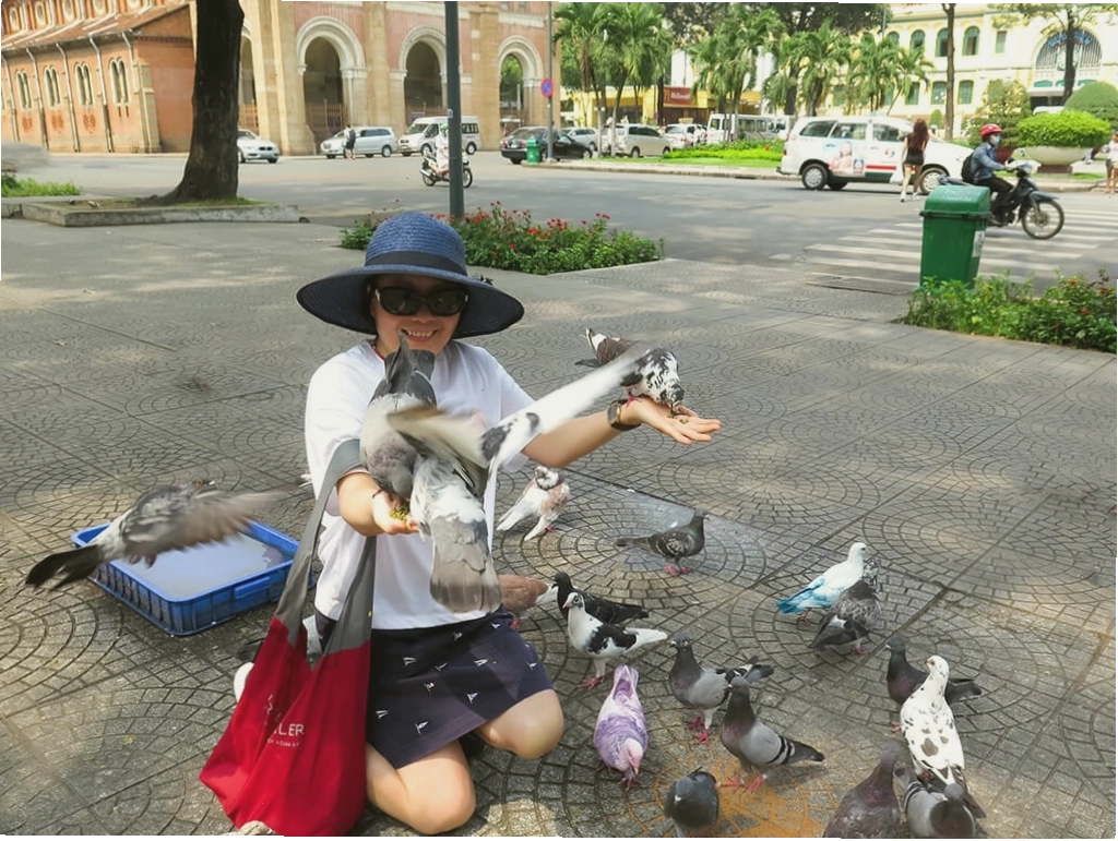 Du khách chụp hình cùng chim bồ câu trước Nhà thờ Đức Bà Sài Gòn