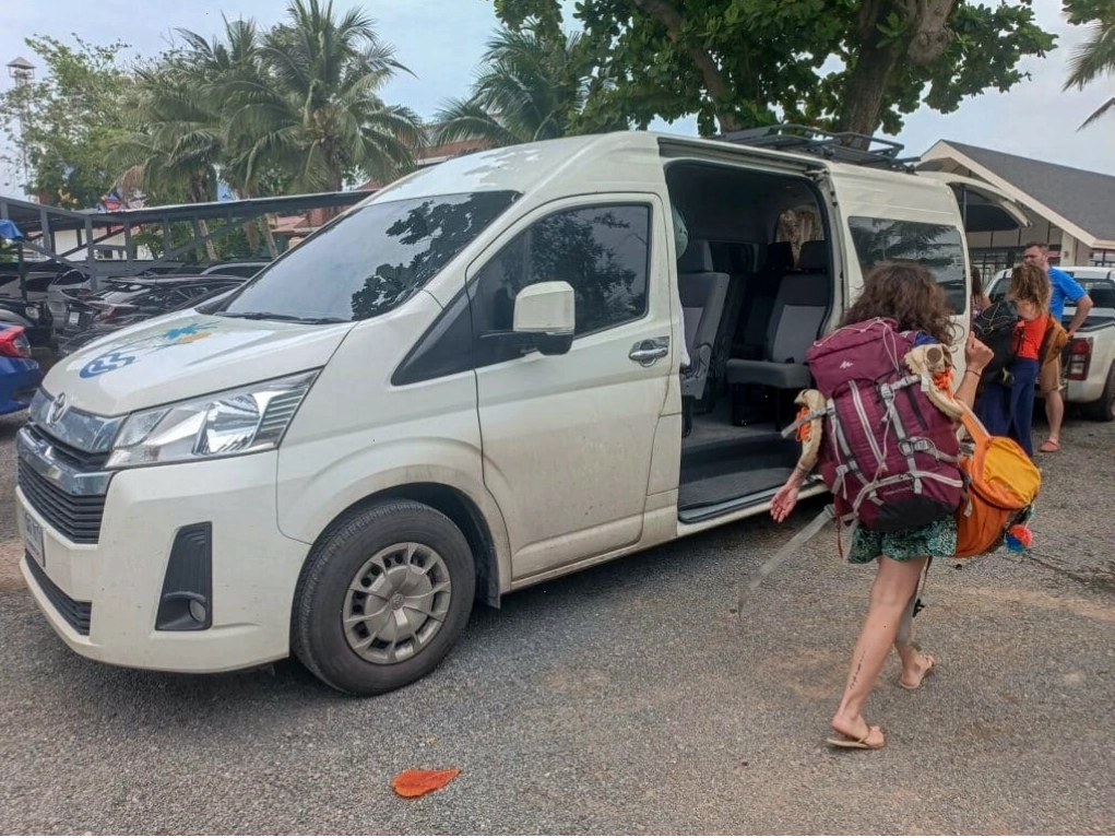 Du khách với ba lô lớn lên xe buýt trắng tại Thái Lan