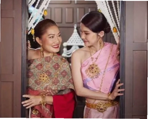 Hai quý cô trong bộ trang phục Thái Lan tinh xảo, mỉm cười và hé nhìn từ sau cánh cửa, thể hiện tình chị em thân thiết.