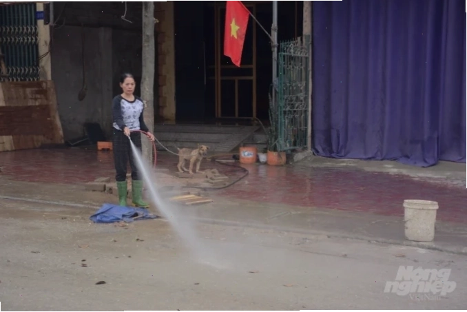 Người dân xịt rửa bùn đất trước cửa nhà