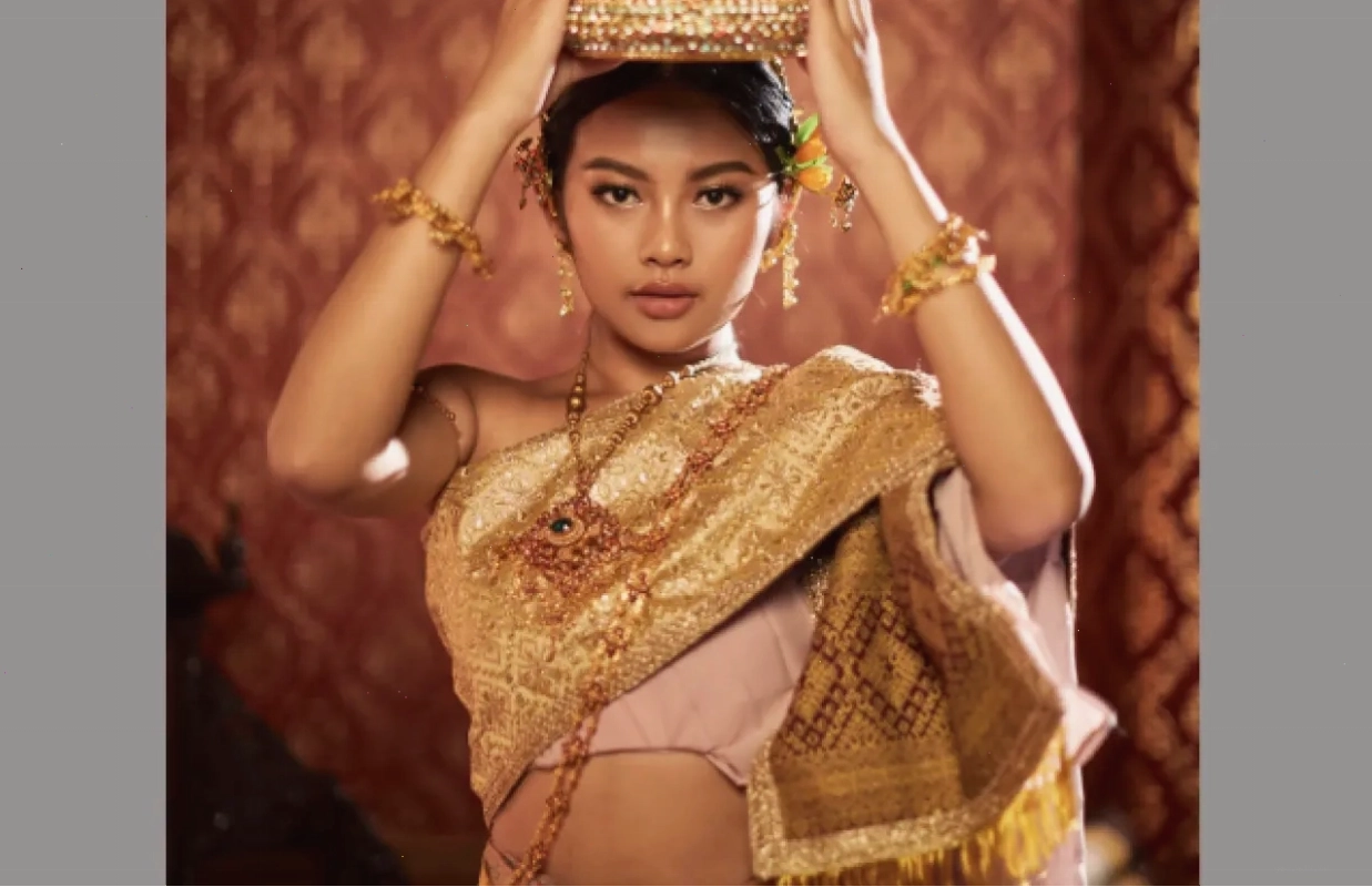 Phụ nữ mặc bộ trang phục Thái màu vàng tím lộng lẫy và vương miện vàng, thể hiện vẻ đẹp cổ điển và hiện đại.