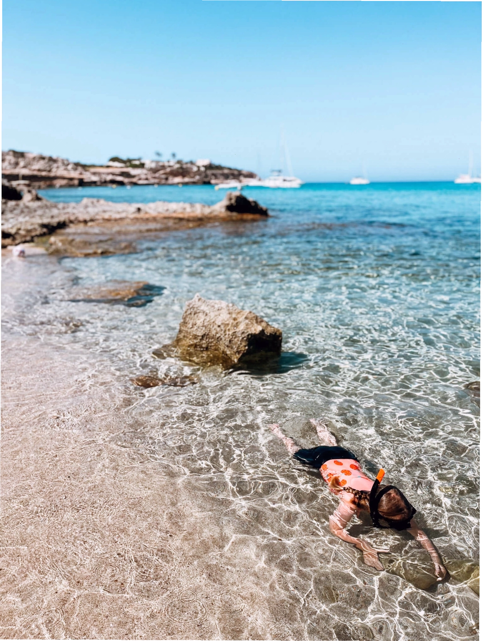 Trẻ em đang lặn biển ở vùng nước nông, trong vắt tại Cala Comte, Ibiza